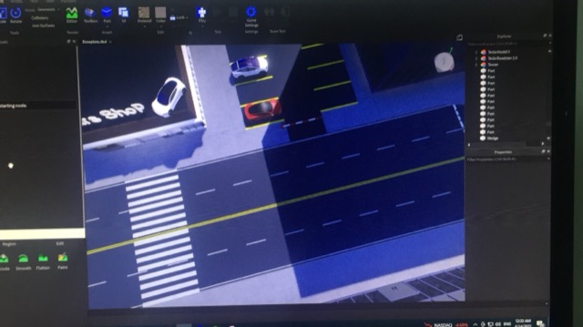 A photo of Roblox Studio showing a road, a crossing and a car showroom in an unfinished game.